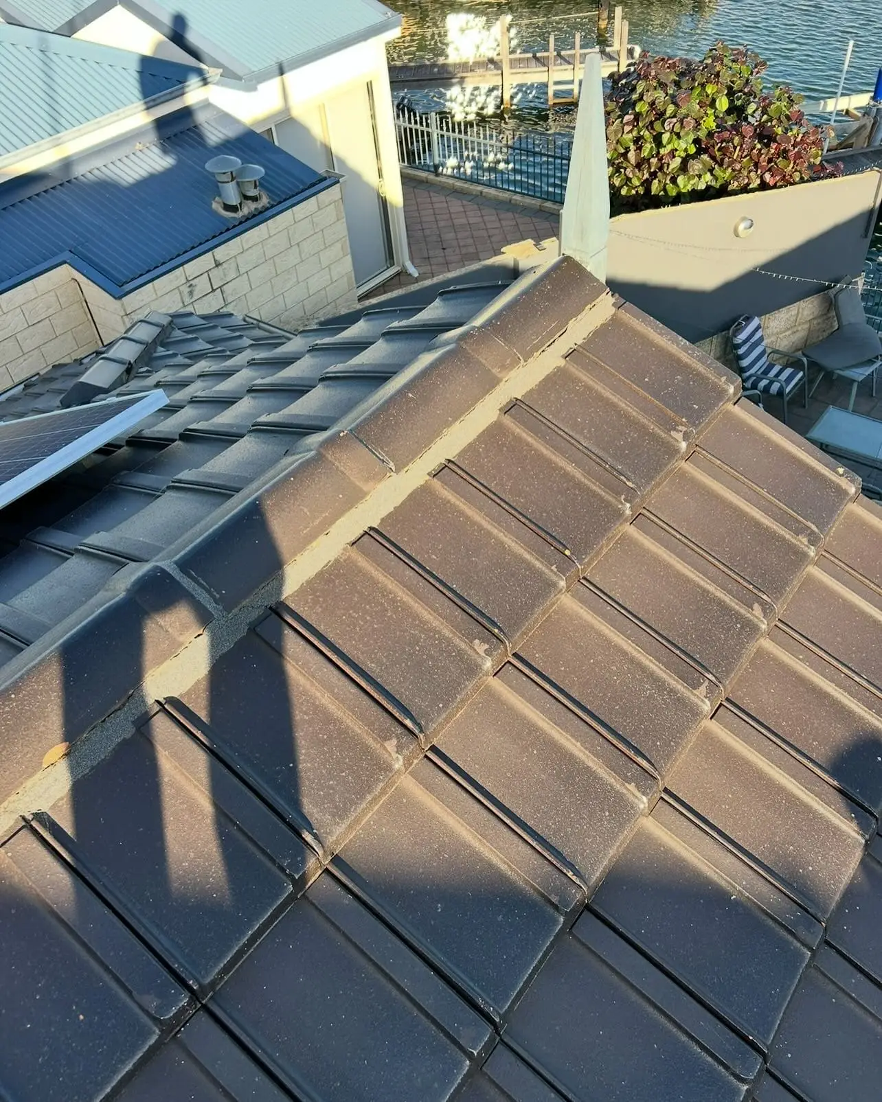 Charcoal tiled roof with a waterway and boats beyond the house