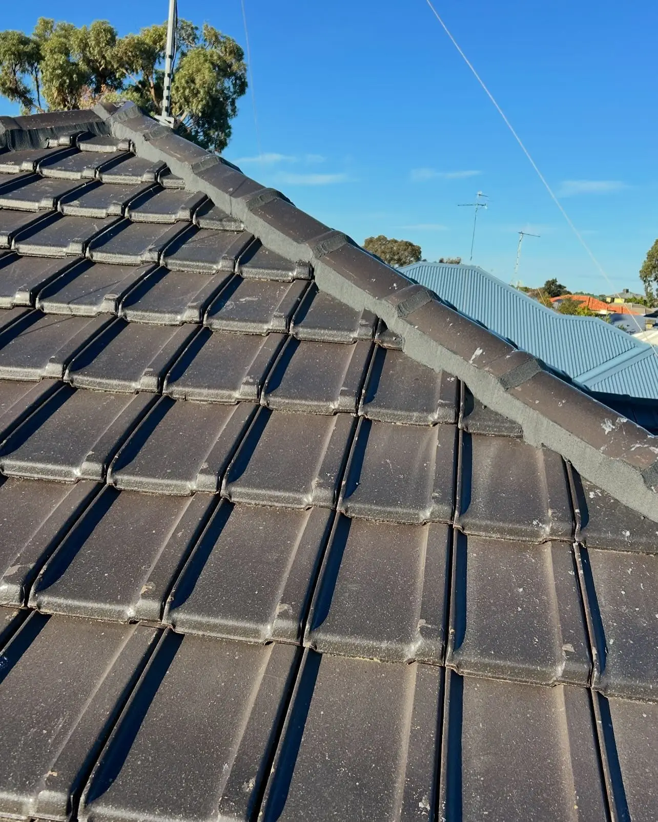Repointed hip line on a charcoal tiled roof under a blue sky