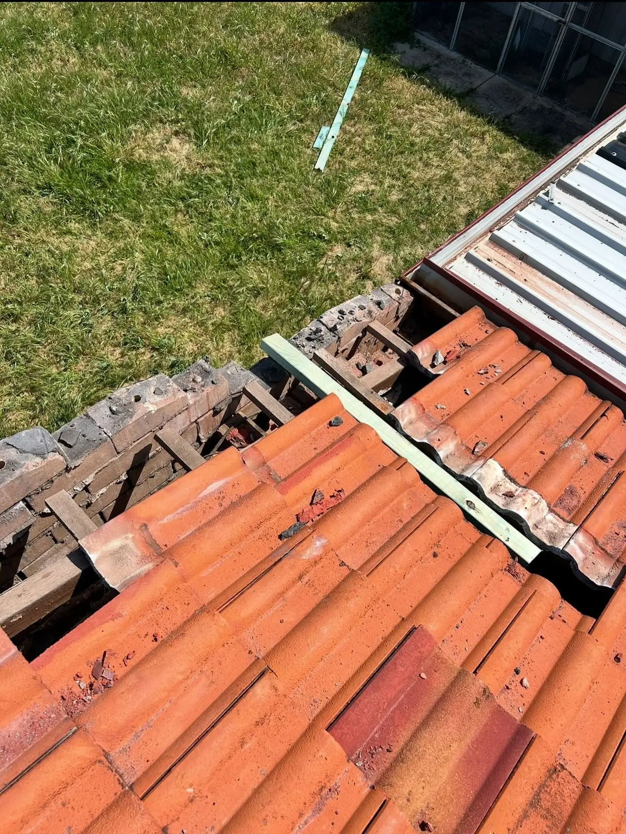 Terracotta roof tiles lifted beside a section under repair