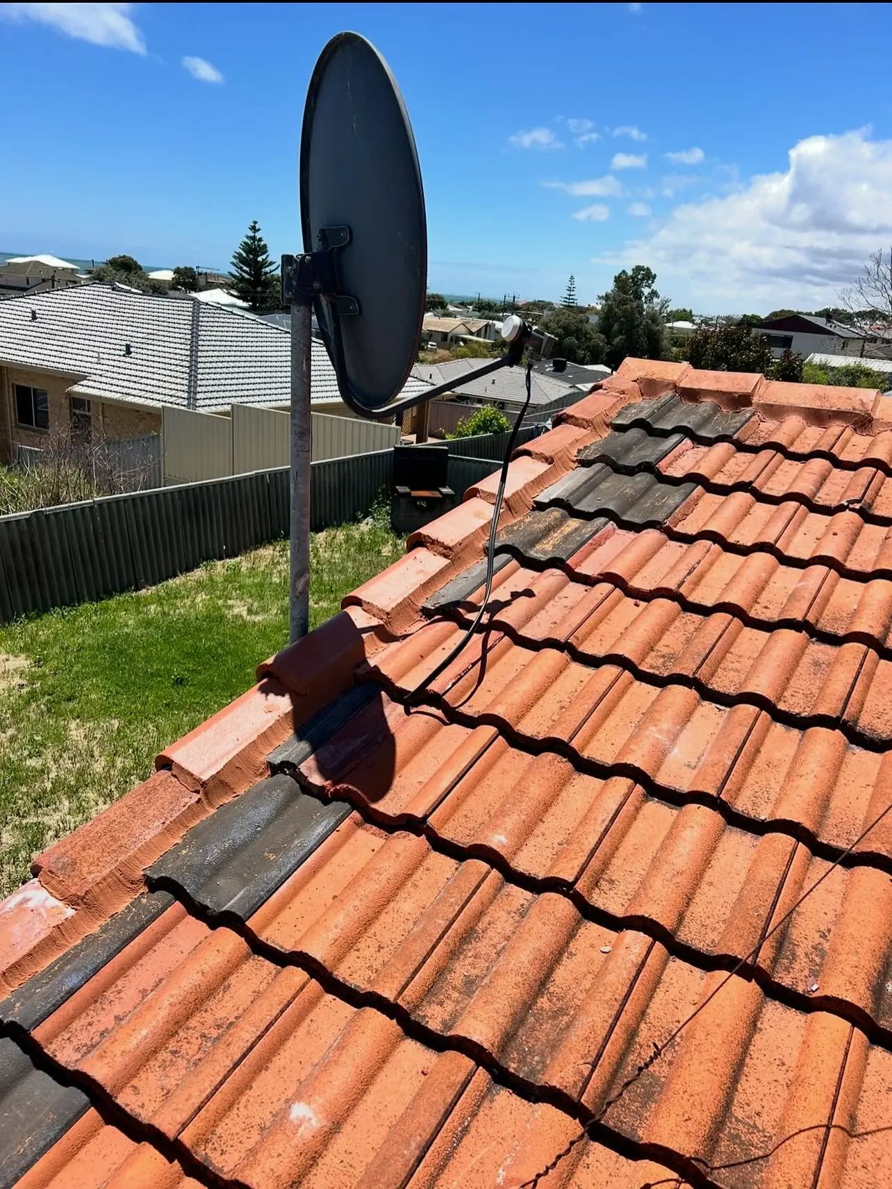 Terracotta roof with a satellite dish and a repaired ridge