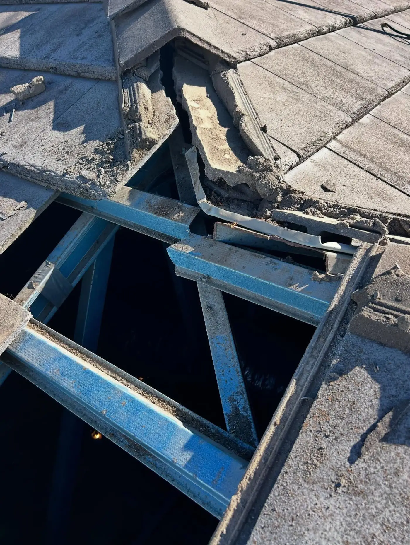 Ridge opened up on a grey tile roof, steel battens and rafters below