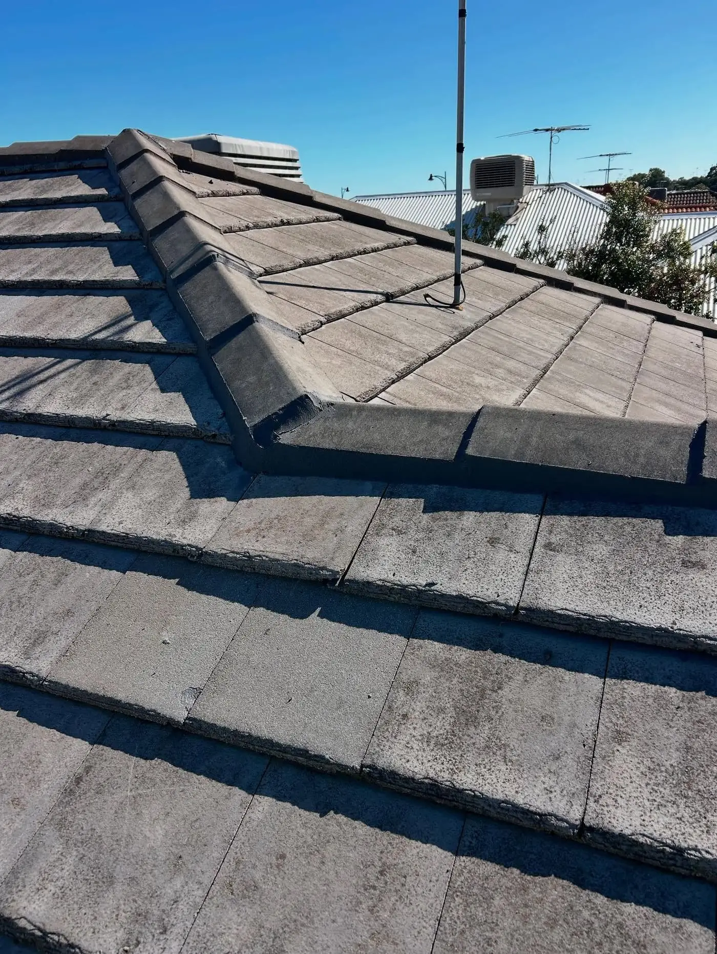 Finished grey concrete tile hip roof under a clear sky