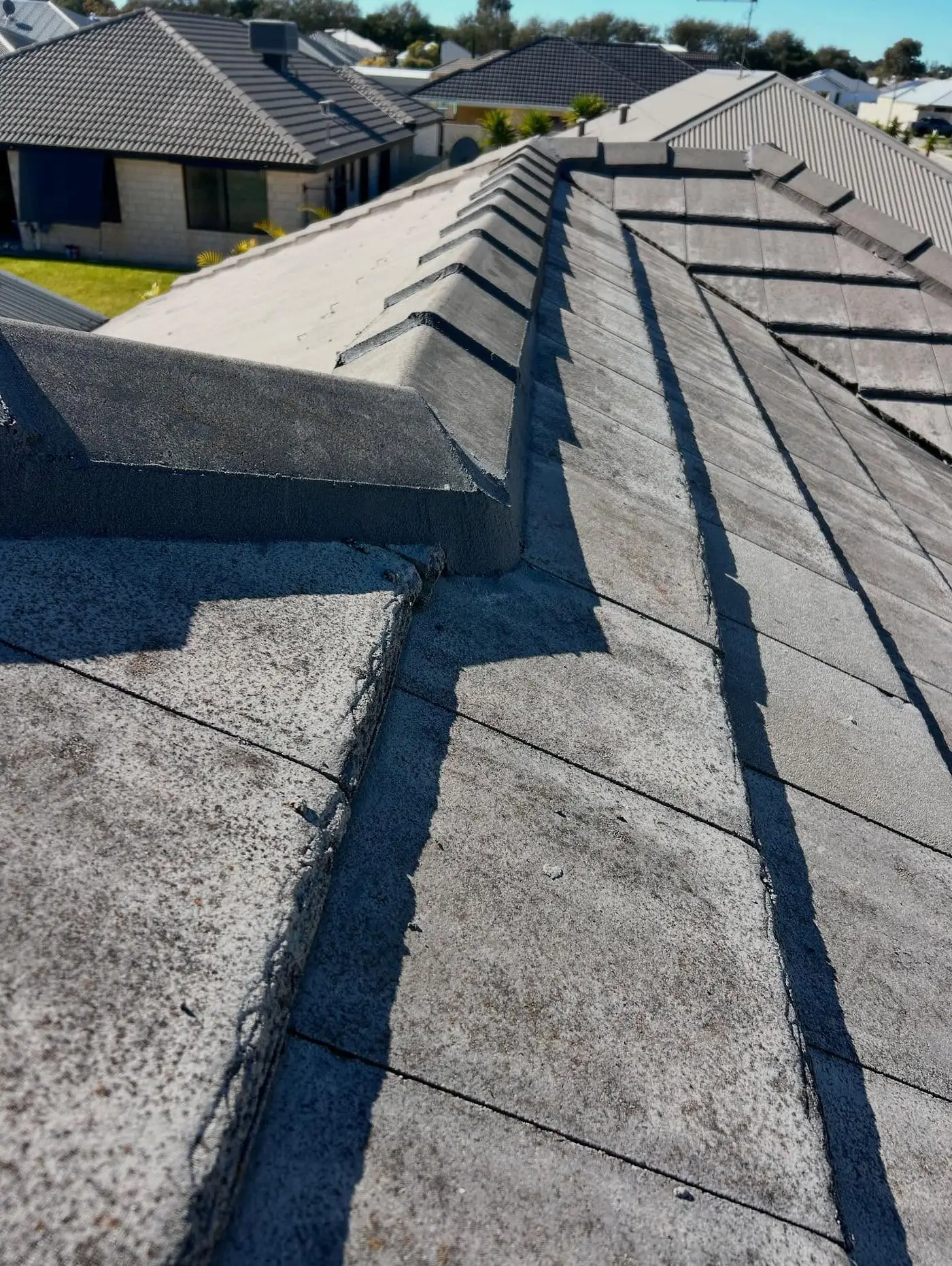 Grey tile hip roof with neighbouring homes in the background