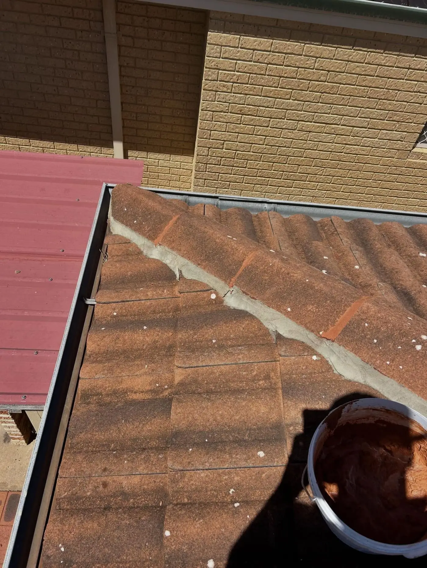 Fresh pointing along a terracotta valley with a mortar bucket