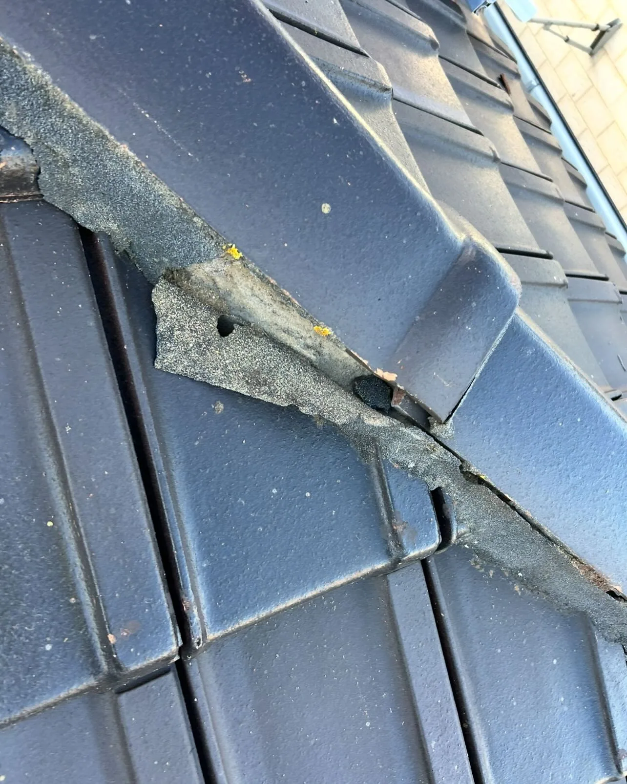 Close view of cracked and separated pointing beside dark ridge tiles